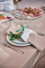 Table setting with sparkling wineglasses, plate with beige napkin and cutlery on table, copy space. Place set at wedding reception. Table served for wedding banquet in restaurant