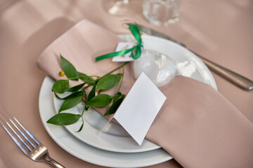Table setting with plate, beige napkin and cutlery on table, copy space. Place set at wedding reception. Table served for wedding banquet in restaurant