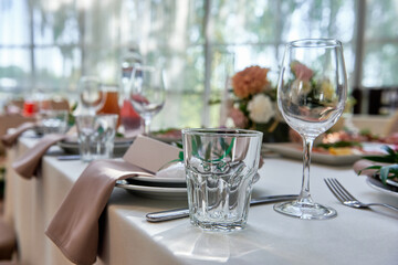 Table setting with sparkling wineglasses, plate with beige napkin and cutlery on table, copy space. Place set at wedding reception. Table served for wedding banquet in restaurant