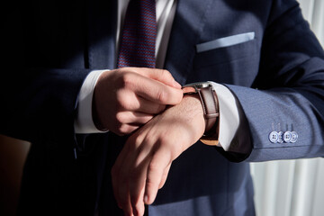 Close up of watches on male hand indoors, copy space. Man in suit checking time from luxury...