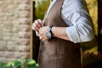 Man in white shirt buttoning waistcoat in room indoors, close up. Businessman dressing up. Fashion,...