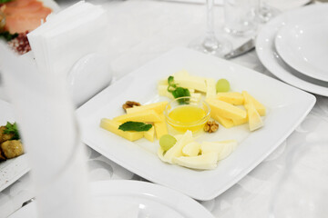 Plate with assortment of cheese and honey on dinner table, copy space. Cheese plate. Holiday concept