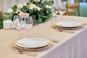 Table setting with sparkling wineglasses, plate with white napkin and cutlery on table, copy space. Place set at wedding reception. Table served for wedding banquet in restaurant