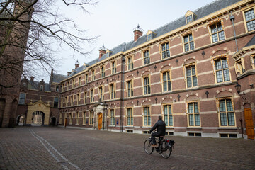 Obraz premium Europe, Netherlands, The Hague. Cyclist rides toward entrance to Binnenhof.