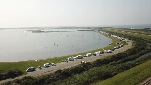 Line of campers parked and people windsurfing on Brouwersdam in The Netherlands during a summer day