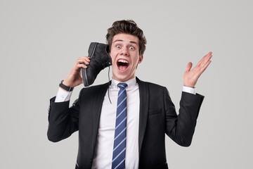 Excited crazy worker talking on boot as on smartphone