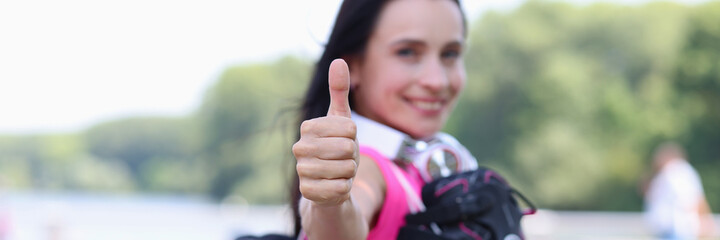 Smiling woman with rollers on shoulder showing thumb up closeup