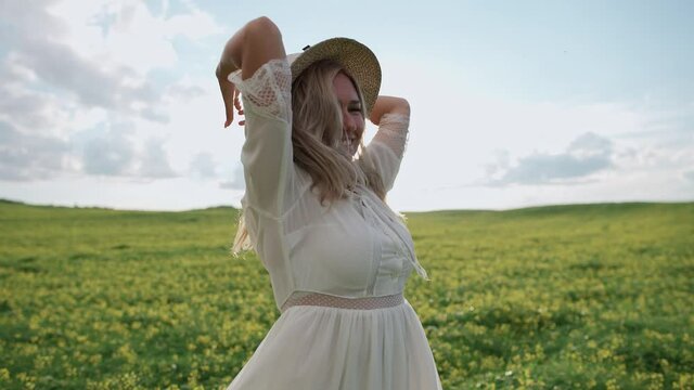 Countryside, cheerful woman in white dress dancing in the field of rapeseed, 4k slow motion.