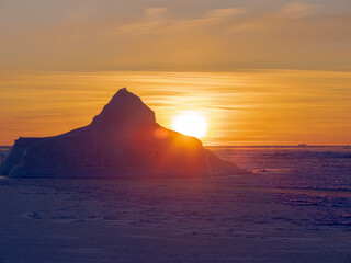 Fototapeta na wymiar Sunset at the shore of frozen Disko Bay during winter, West Greenland, Denmark