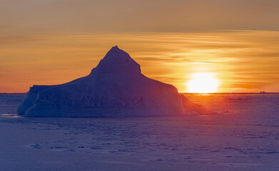 Fototapeta na wymiar Sunset at the shore of frozen Disko Bay during winter, West Greenland, Denmark