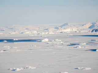 Fototapeta na wymiar Sea ice with icebergs in the Baffin Bay, between Kullorsuaq and Upernavik in the far north of Greenland during winter.