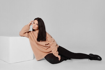 Adorable model girl with black hair wearing fashionable sweatshirt posing over white background