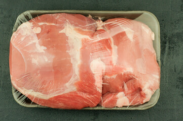 Fresh steamed pork tenderloin on a black plastic tray is hermetically sealed. top view. black...
