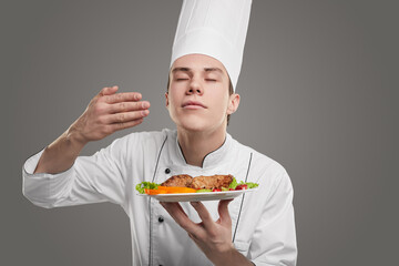 Satisfied chef smelling dish on plate