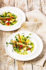 Gourmet fish salad. Pangasius dori fillet, vegetables, avocado pate, mozzarella and fresh herbs. Restaurant serving. Chef's dish. Healthy and tasty food on a wooden background. Ketogenic diet dishes.