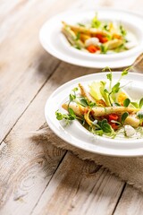 Close-up gourmet fish salad. Pangasius dori fillet, vegetables, avocado pate, mozzarella and fresh herbs. Restaurant serving. Healthy and tasty food on a wooden background. Ketogenic diet dishes.