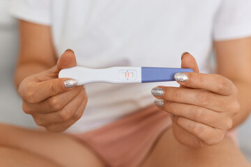 Portrait of unknown faceless woman with manicure showing pregnancy test with positive result, pregnancy, women's health.