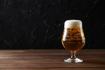 Glass beer with bubbles on wood background with copyspace