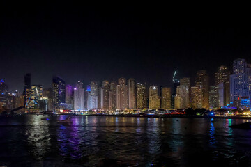 Fototapeta premium Panoramic view at night of Business Bay district with reflection in sea, UAE. Aerial sky at highest buildings in central Dubai, United Arab Emirates. High quality photo