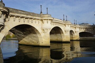 Obraz premium reflection in seine river of pont neuf bridge with stone arches and carved faces paris france