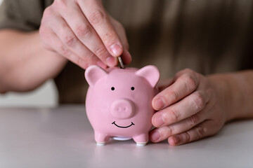 Businessman putting coin into small piggy bank