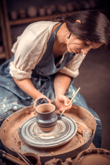 Fototapeta na wymiar Charming young and cheerful woman demonstrates the process of making ceramic dishes using the old technology. Handmade products.