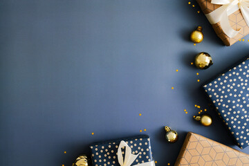Dark blue Christmas background with gift boxes and gold baubles. Flat lay, top view, copy space.
