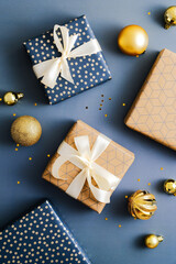 Fototapeta na wymiar Christmas gifts and gold baubles on dark blue background. Elegant Christmas flat lay composition. Happy New Year and Merry Christmas concept.
