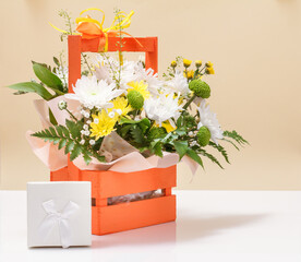 Beautiful bouquet of yellow and white flowers with wooden basket.