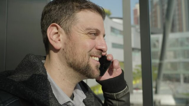 Side view close up happy businessman people in the elevator talking on the mobile phone on the way to the office at sunny day in urban city 