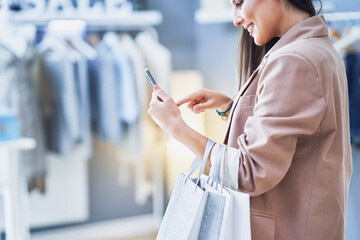 Nice woman with phone in clothes store