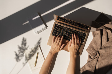 Flatlay of person hands working on laptop computer. Aesthetic bohemian home office workspace. Work...