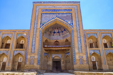 Fototapeta na wymiar Facade portal of Muhammad Rahim Khan madrasah decorated with traditional patterns, Khiva, Uzbekistan. Niches of students' rooms are visible. It was one of largest madrasahs in city. Built in 1871
