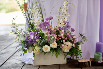 Beautiful floral arrangement of purple flowers and greenery on the floor in restaurant, copy space. Luxury wedding decorations. Table setting