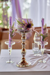 Beautiful floral arrangement and candles in candlestick on wedding table in restaurant, copy space. Luxury wedding decorations