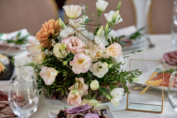 Beautiful floral arrangement of rose flowers and greenery on wedding table in restaurant, copy space. Luxury wedding decorations. Table setting