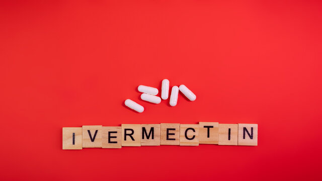 Ivermectin on colored red paper texture background. Ivermectin antiparasitic medication. Off label approved medicine drugs use. Covid-19 therapy. Pharmacy concept. Copy space. Mock up design template