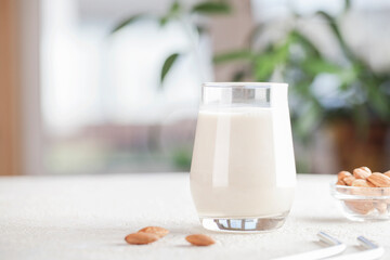 Vegan almond milk in glass with nuts on blurry background. Copy space. Healthy vegetarian food. selective focus. Non dairy alternative milk - obrazy, fototapety, plakaty