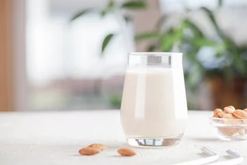 Fotobehang Vegan almond milk in glass with nuts on blurry background. Copy space. Healthy vegetarian food. selective focus. Non dairy alternative milk © Анна Мартьянова