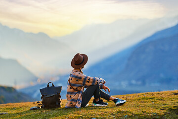Hipster man traveler wanderer wearing hat sitting alone and enjoying freedom and calm inspired travelling - obrazy, fototapety, plakaty