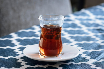 Turkish tea in a traditional glass on a white saucer.  The Tulip shaped glass is called ince belli meaning slim-waisted.  © Audrey
