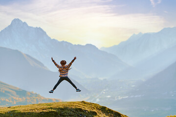 Happy hipster man traveler wanderer jumping with open arms and enjoying freedom and calm inspired travelling