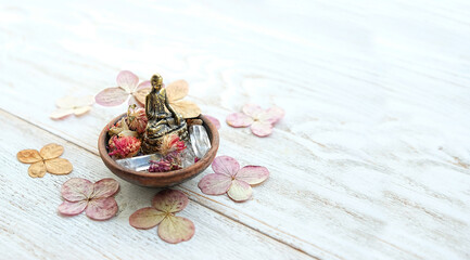 quartz minerals, little Buddha statue, dried flowers on white wooden table close up. Healing...
