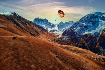 Parachutist flies over a picturesque scenic mountain valley. Enjoying of flying in the air with a...