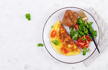 Omelette with tomatoes, ham, cheese and corn salad on plate.  Frittata - italian omelet. Top view, overhead