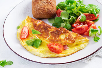 Omelette with tomatoes, ham, cheese and corn salad on plate.  Frittata - italian omelet.