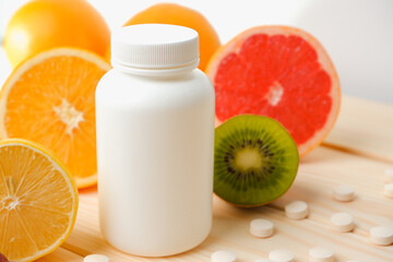 Vitamins. Medical concept. Pharmacy or natural. White bottle with vitamins, scattered pills. Juicy ripe citrus fruit slices. lemon. Orange. Grapefruit.