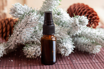brown glass bottle on the background of snow-covered fir branches and cones