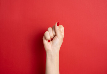 84 / 5.000 Çeviri sonuçları Female hand with red nails on red background, space for text ,...
