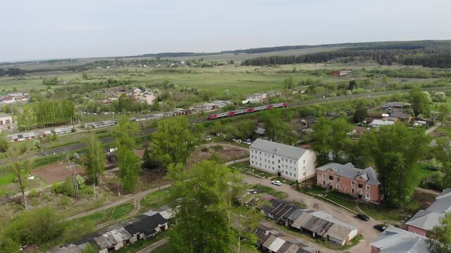 Aerial view of an electric train passing by the village (Strizhi, Kirov region, Russia)